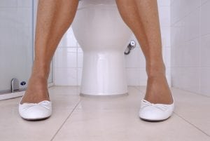 legs of a person sitting on a toilet