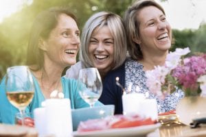 three female friends laughing around a table