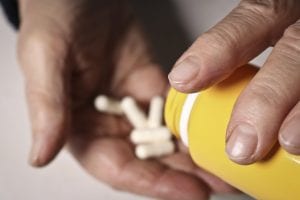 patient pouring medication out of the bottle into their hand