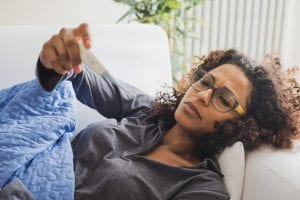 woman feeling sick and looking a thermometer