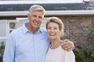 happy senior couple smiling in front of their house